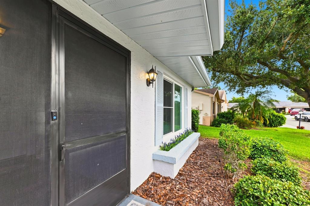 A white house exterior features a screen door, a window with shutters, and a planter box — 1425 LELAND DRIVE, SUN CITY CENTER, FL