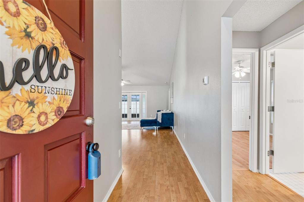 A view from an entryway into a living area with wood-look flooring and white walls — 12008 PEONY COURT, TAMPA, FL