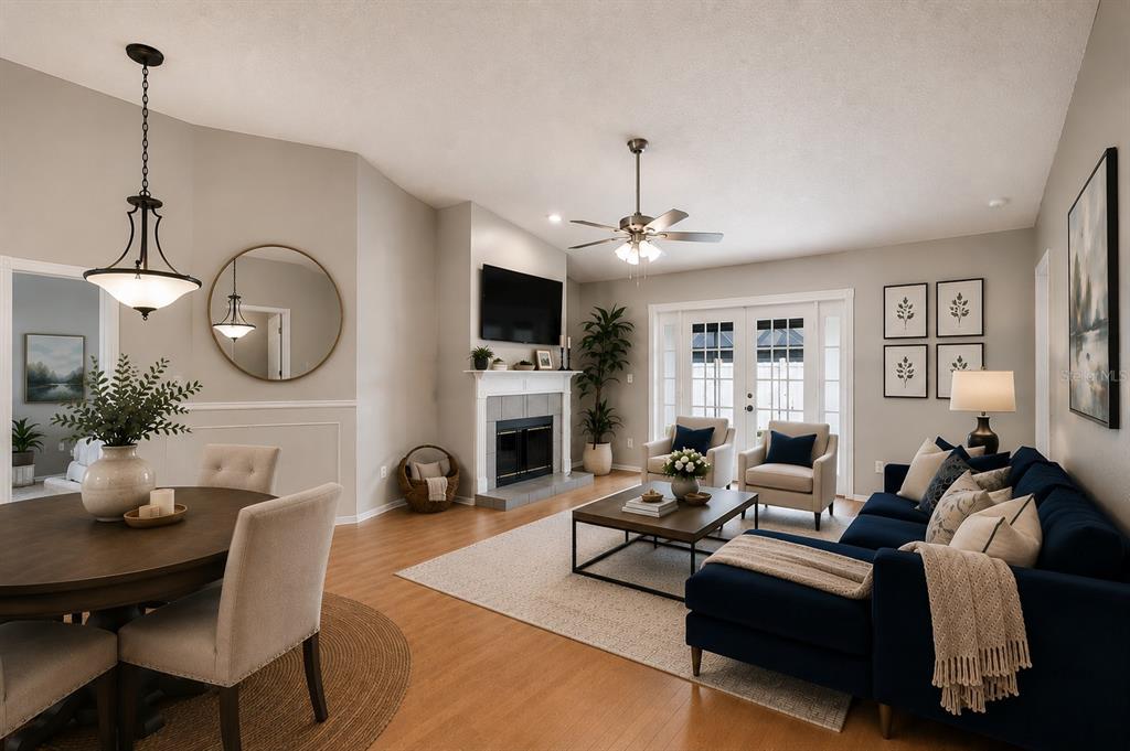A living room and dining area with a fireplace, navy sofa, and light wood floors — 12008 PEONY COURT, TAMPA, FL