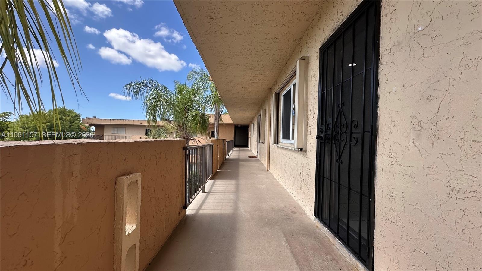 An outdoor walkway with a metal railing and a security door leads along a building — 8401 SW 107th Ave # 331E, Miami FL 33173, MIAMI, FL
