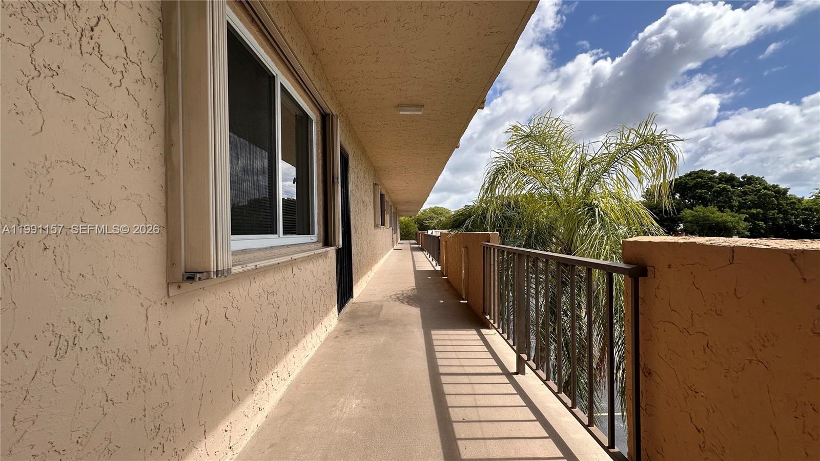 An outdoor walkway with a metal railing runs alongside a building with stucco walls — 8401 SW 107th Ave # 331E, Miami FL 33173, MIAMI, FL