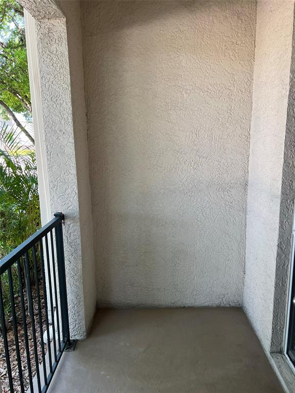 A covered outdoor patio features a concrete floor, stucco walls, and a black metal railing — 402 S ARMENIA AVENUE UNIT 114, TAMPA, FL