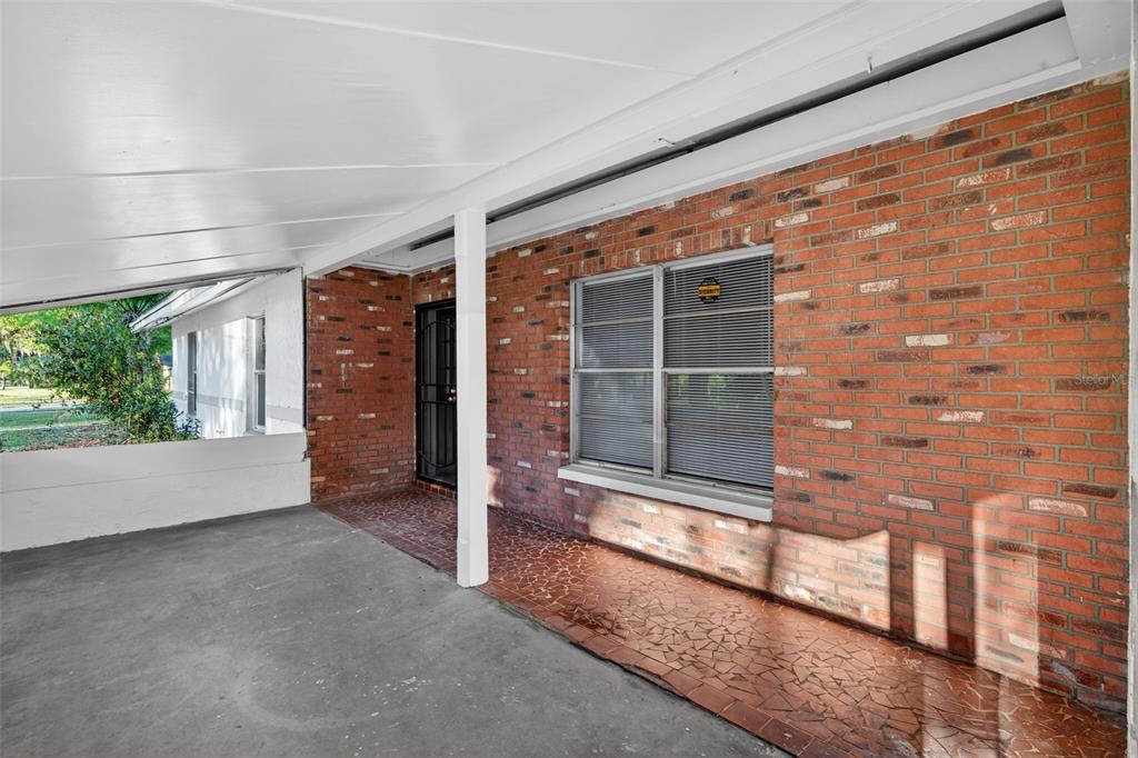 A covered patio with a concrete floor, brick wall, and a window with blinds — 1941 BROWN ROAD, ALVA, FL