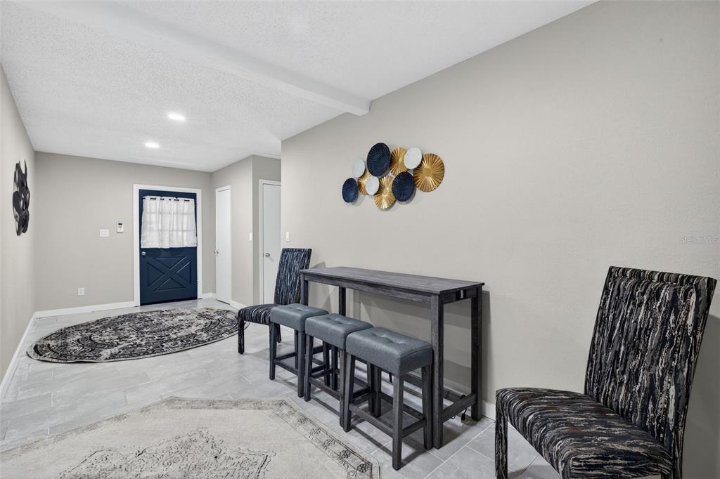 A dining area features a tall wooden table with three stools and two patterned chairs — 1941 BROWN ROAD, ALVA, FL