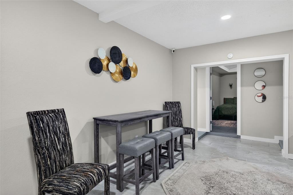 A dining area features a gray wooden table, four stools, and patterned chairs — 1941 BROWN ROAD, ALVA, FL