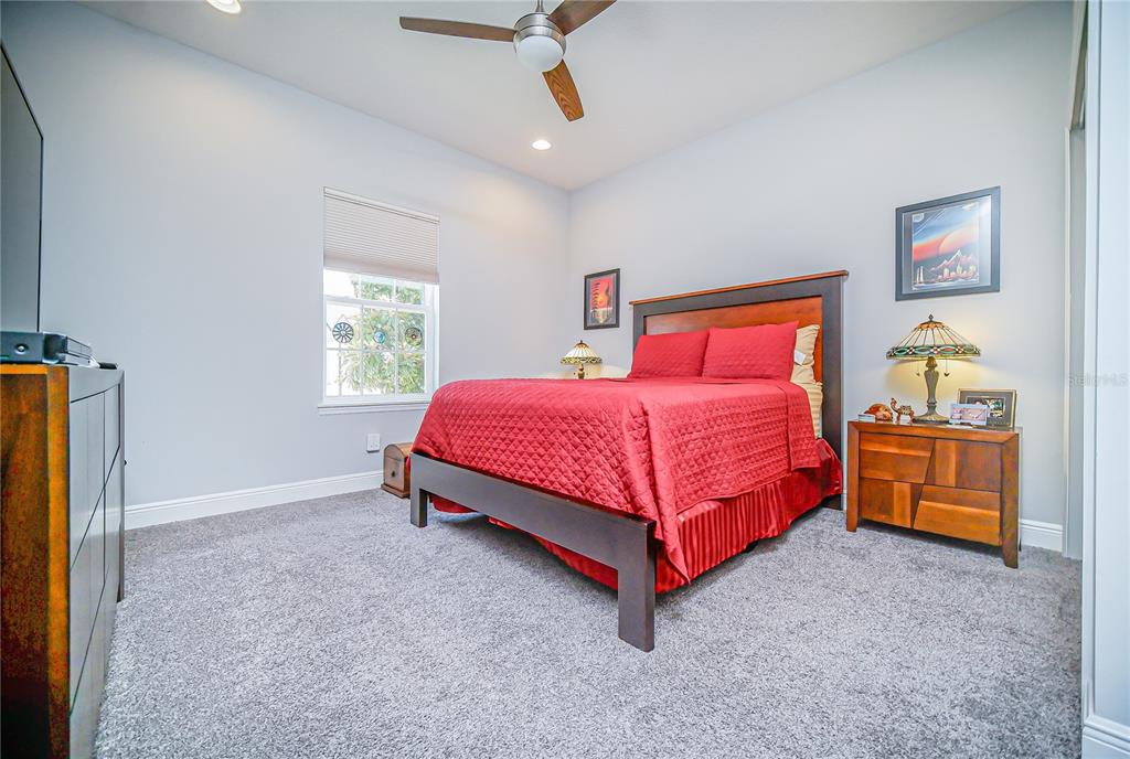 A bedroom features a queen bed with red bedding, a ceiling fan, and gray carpet — 2389 PEARL CIDER STREET, ORLANDO, FL