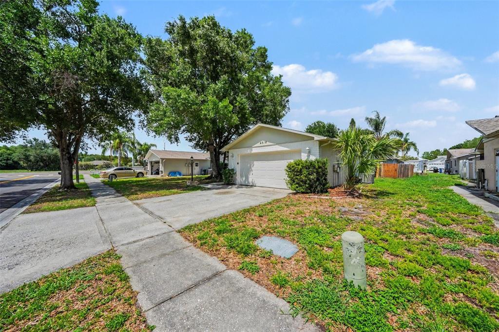 A single-story house with a white garage and a concrete driveway under large trees — 4816 W ADDAX DRIVE, NEW PORT RICHEY, FL
