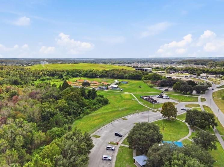 An aerial view shows a park with a dirt bike track, parking lot, and surrounding trees — 5117 CHATTAHOOCHEE BEND, ST CLOUD, FL