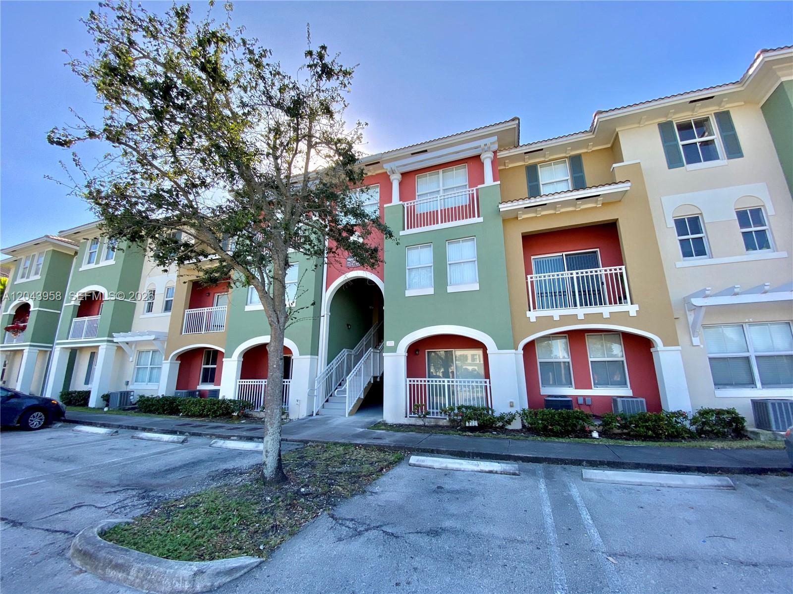 A multi-story apartment building features colorful stucco walls, balconies, and a central outdoor staircase — 11202 NW 83rd St # 106, Doral FL 33178, DORAL, FL