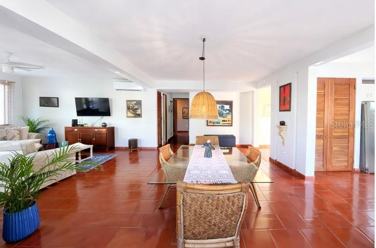 A dining area with a rattan pendant light and glass table sits beside a living room — Principal E1 LAKESIDE VILLAS, VEGA ALTA, PR