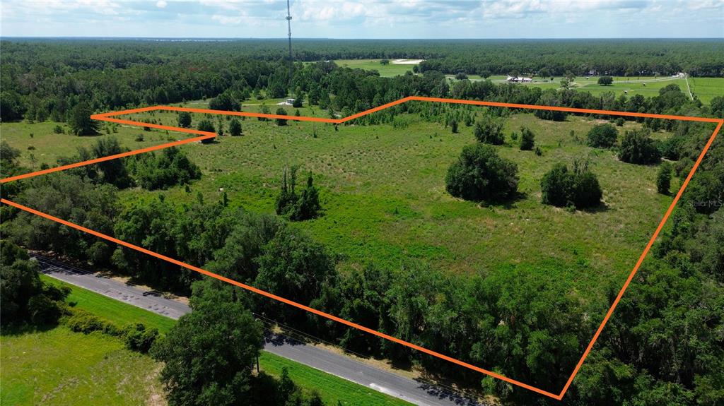 An aerial view shows a large, undeveloped grassy lot outlined in orange near a road — SW 41ST PLACE, OCALA, FL
