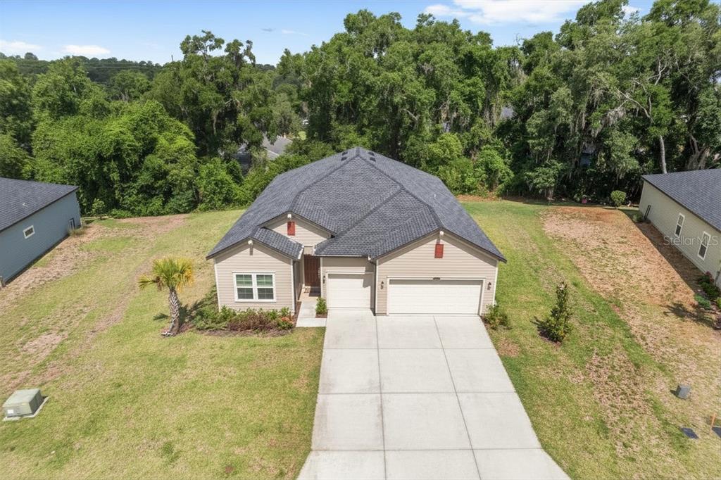 An aerial view of a single-story suburban house with a three-car garage and driveway — 19581 SW 77TH PLACE, DUNNELLON, FL
