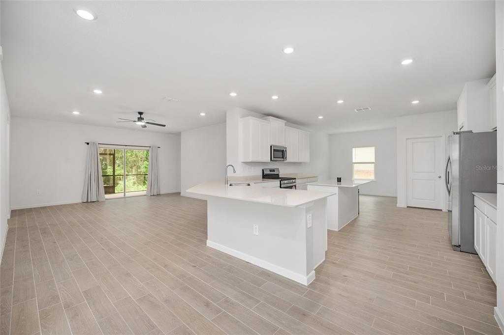 An open-concept kitchen and living area features white cabinetry, a kitchen island, and tile flooring — 19581 SW 77TH PLACE, DUNNELLON, FL
