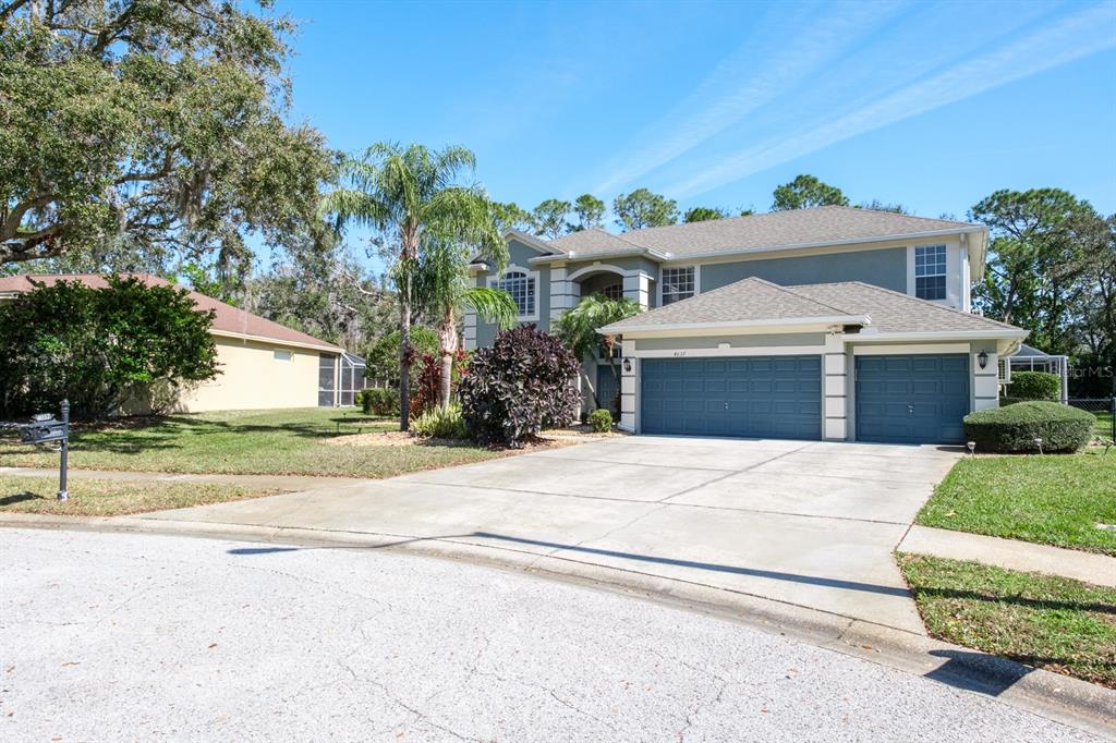 A two-story house with a three-car garage, a concrete driveway, and a landscaped front yard — 4037 AUSTON WAY, PALM HARBOR, FL