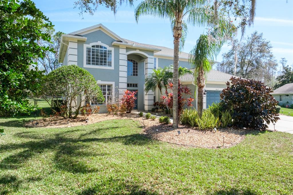 A two-story house with a light blue exterior, white trim, and a landscaped front yard — 4037 AUSTON WAY, PALM HARBOR, FL
