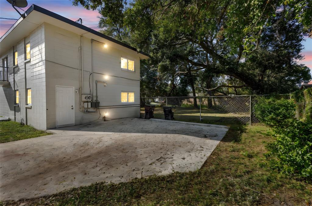 A two-story concrete block building features a white door, exterior lighting, and a concrete driveway — 901 COLYER STREET, ORLANDO, FL