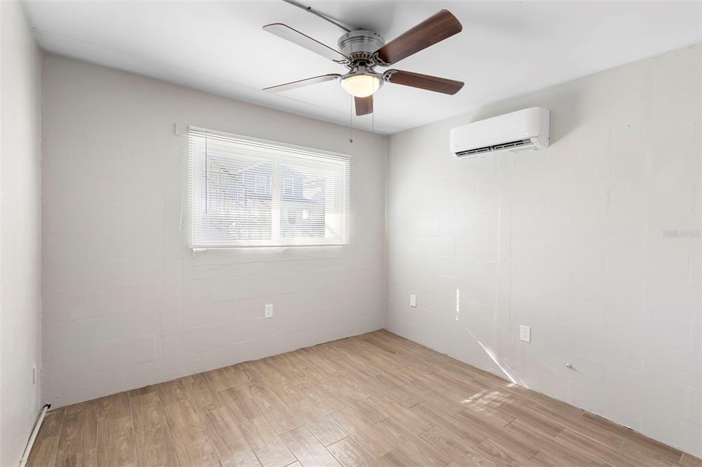 A bedroom with light-colored walls, wood-look tile flooring, a ceiling fan, and a wall-mounted AC — 901 COLYER STREET, ORLANDO, FL