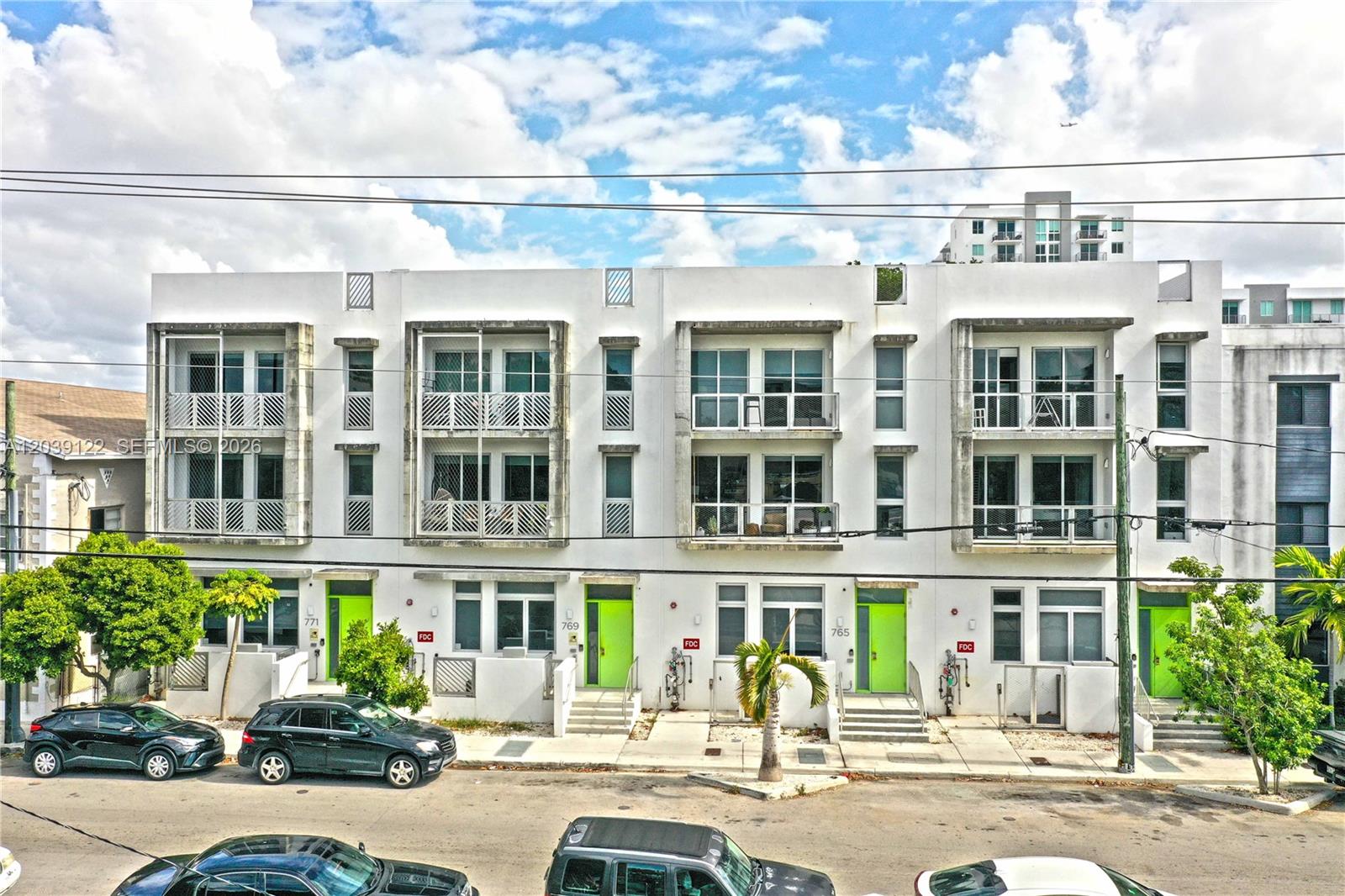 A row of modern three-story townhouses features white facades, lime green front doors, and balconies — 761 NW 1st St, Miami FL 33128, MIAMI, FL