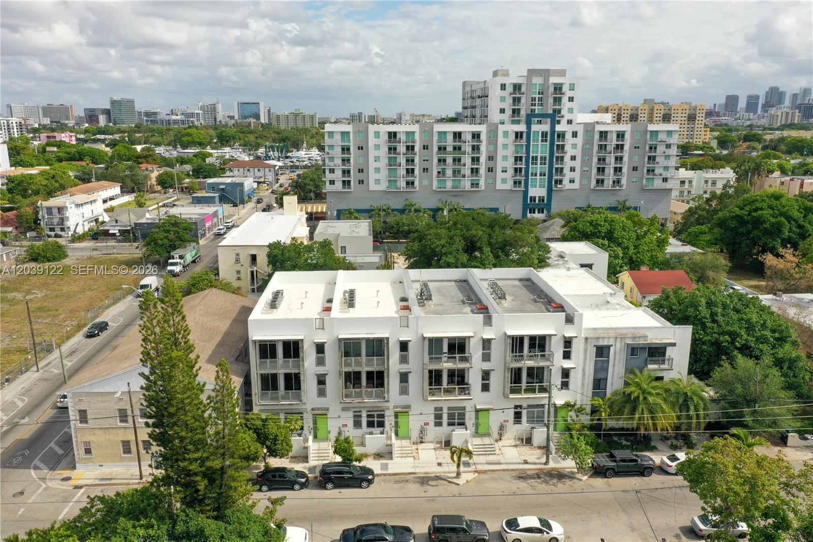 An aerial view shows a modern white townhouse complex situated in a dense urban neighborhood — 761 NW 1st St, Miami FL 33128, MIAMI, FL