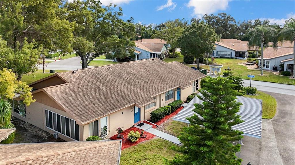 An aerial view shows a single-story duplex with a brown shingled roof and carport — 409 FELTHAM TRAIL UNIT B, SUN CITY CENTER, FL