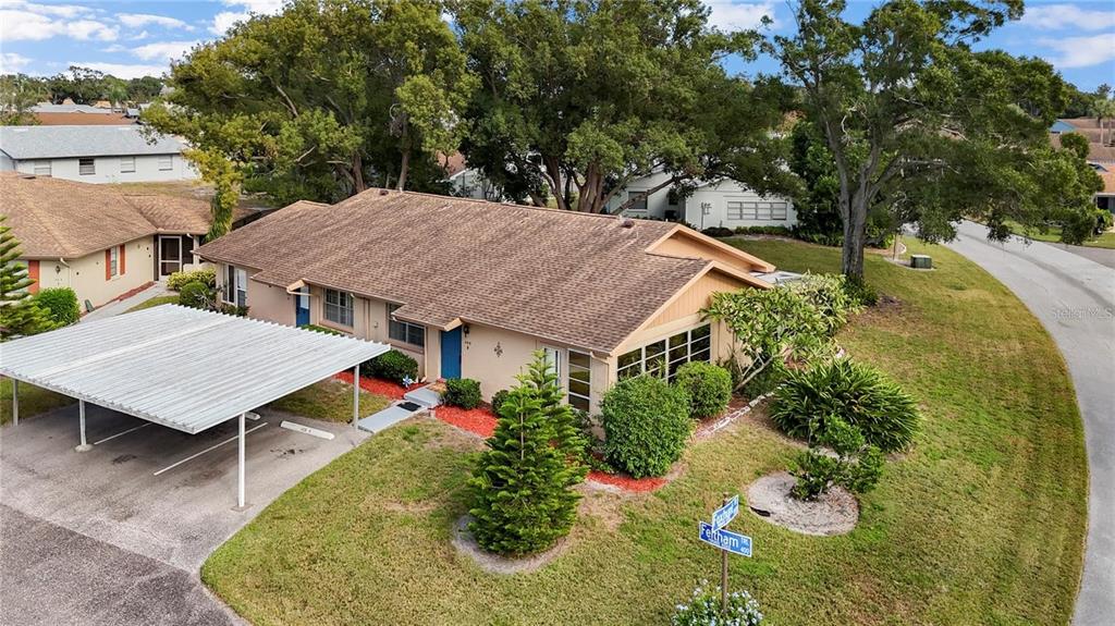An aerial view of a single-story residential building with a carport and surrounding landscaping — 409 FELTHAM TRAIL UNIT B, SUN CITY CENTER, FL