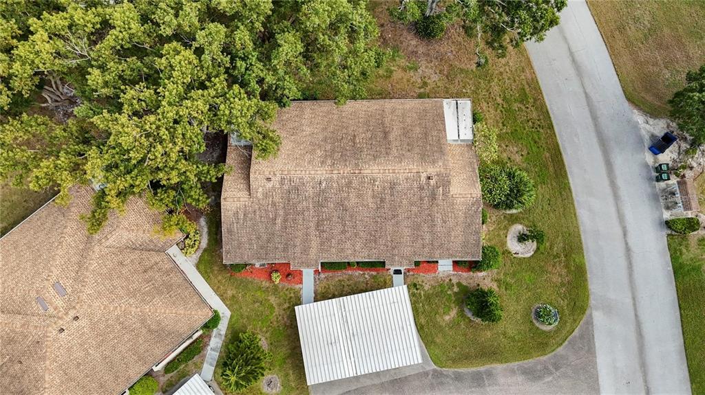 An aerial view shows a house with a brown shingled roof and a metal carport — 409 FELTHAM TRAIL UNIT B, SUN CITY CENTER, FL