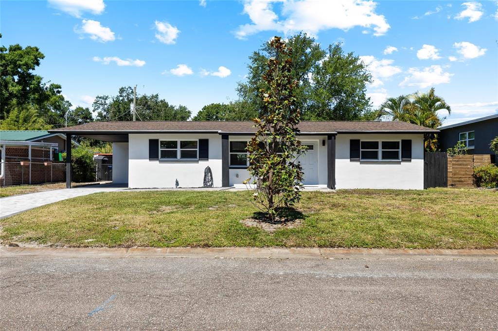 A single-story white house with a carport, black shutters, and a front yard — 4513 S HESPERIDES STREET, TAMPA, FL
