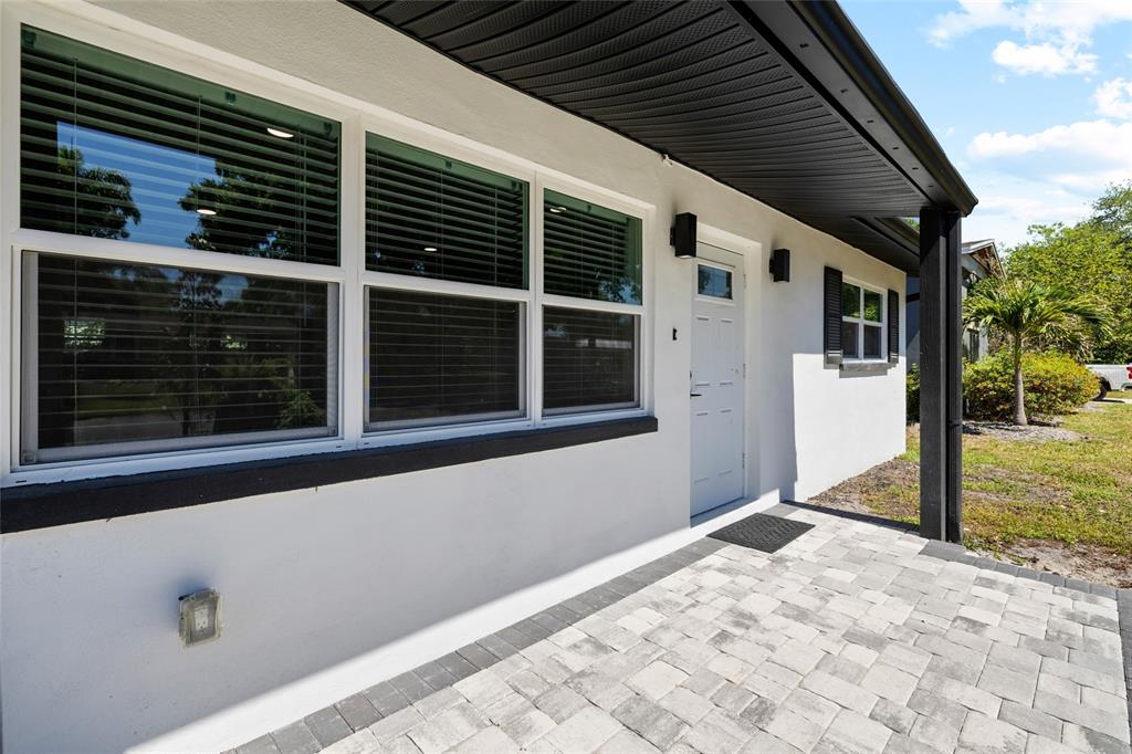 A white house exterior features a paved patio, large windows, and a black roof overhang — 4513 S HESPERIDES STREET, TAMPA, FL