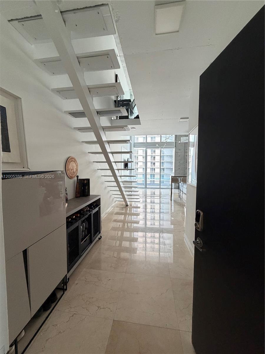 An entryway leads into a modern apartment featuring a white floating staircase and tiled floors — 690 SW 1st Ct # 2524, Miami FL 33130, MIAMI, FL