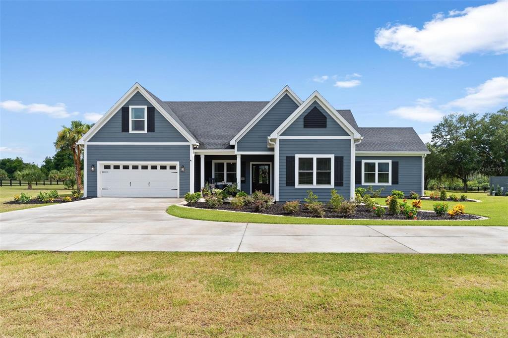 A blue, single-story house with a two-car garage, white trim, and a concrete driveway — 5509 NANTAHALA LANE, LADY LAKE, FL