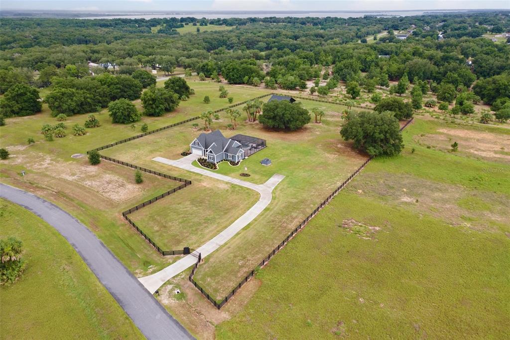 An aerial view shows a single-story house with a pool enclosure on a fenced lot — 5509 NANTAHALA LANE, LADY LAKE, FL