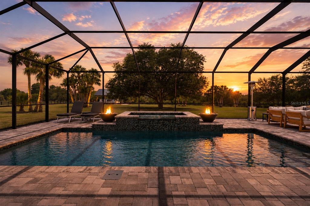 A screened-in pool area features a hot tub, fire bowls, and sunset views — 5509 NANTAHALA LANE, LADY LAKE, FL