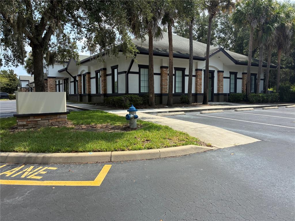 A single-story commercial building with white stucco walls, dark trim, and a brick-accented exterior — 1350 CITY VIEW CENTER, OVIEDO, FL