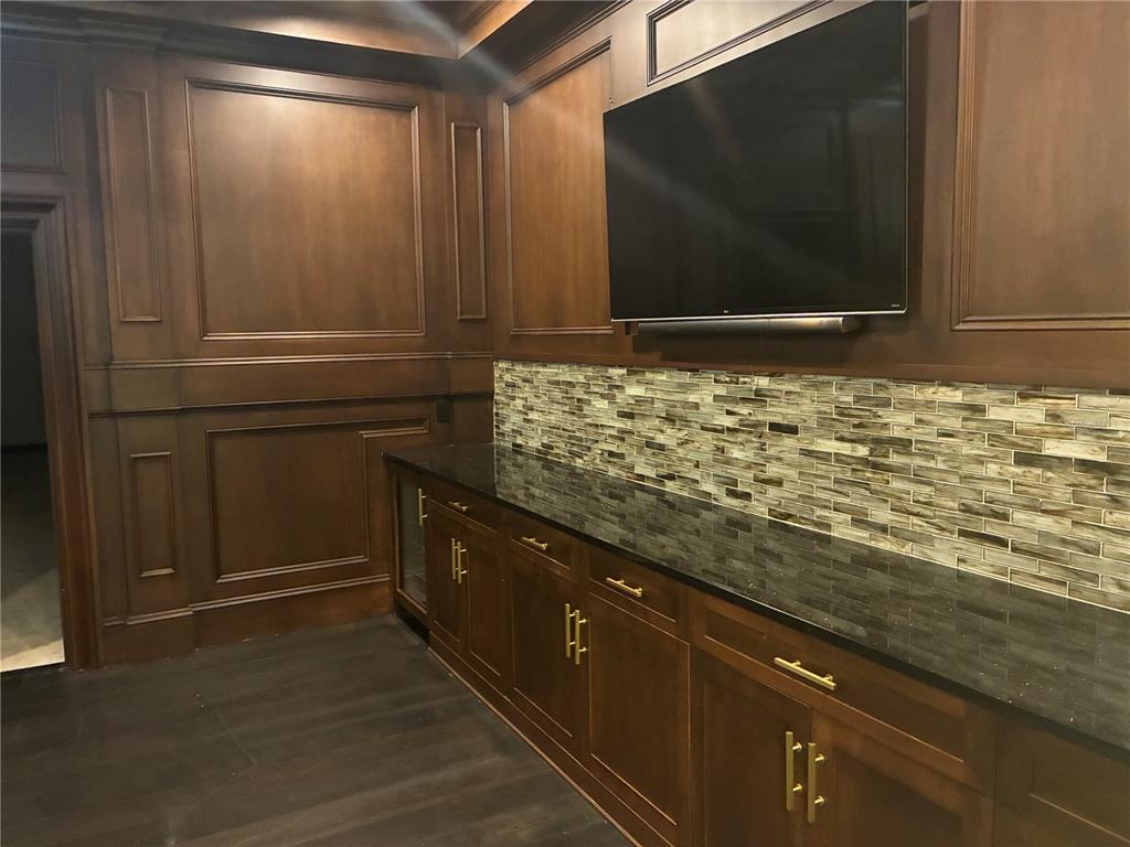 A wet bar features dark wood cabinetry, a black countertop, and a glass tile backsplash — 1350 CITY VIEW CENTER, OVIEDO, FL
