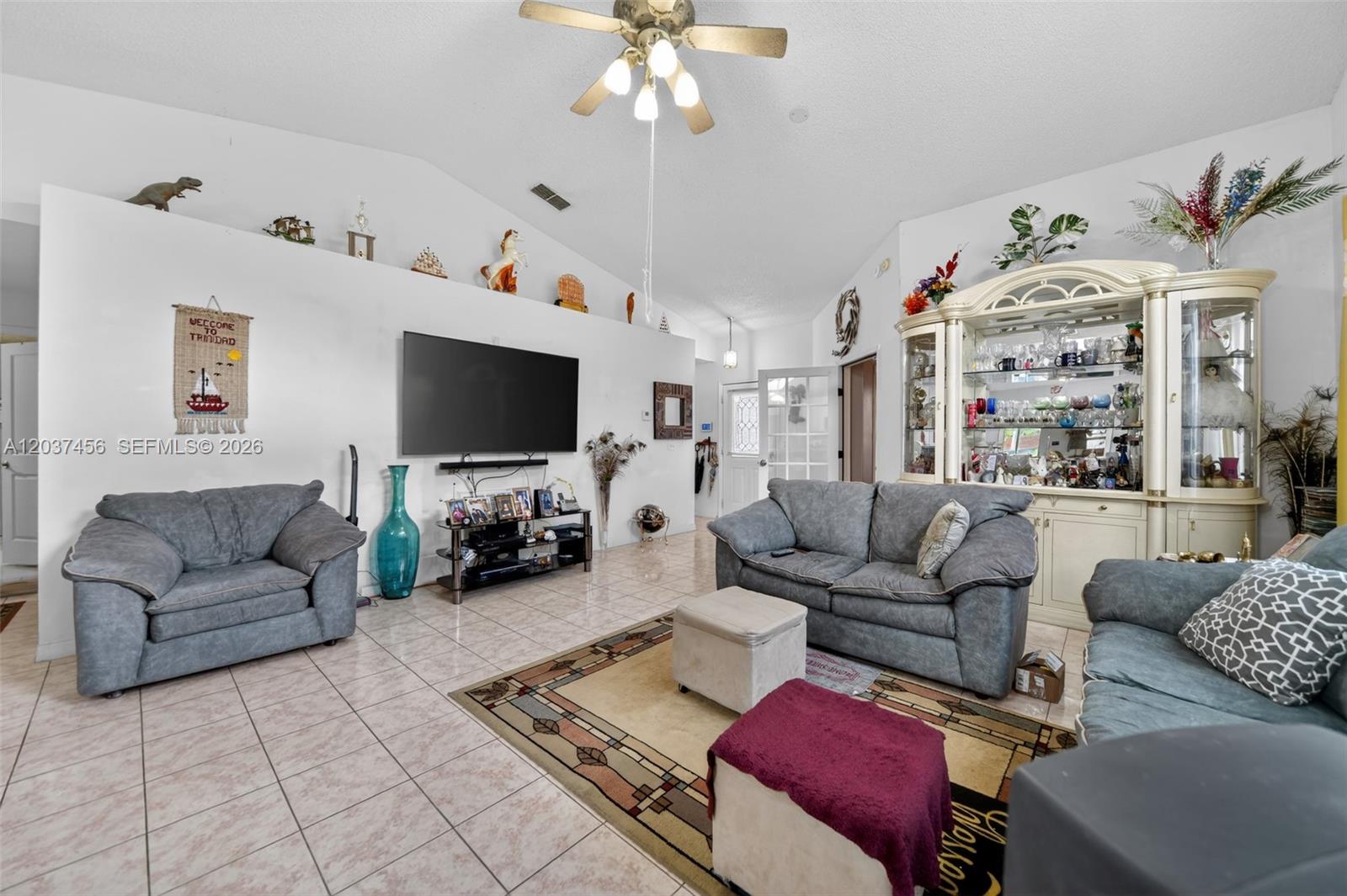 A living room features gray sofas, a large television, and a decorative display cabinet — 362 WHITE MARSH CIRCLE, Orlando FL 32824, ORLANDO, FL