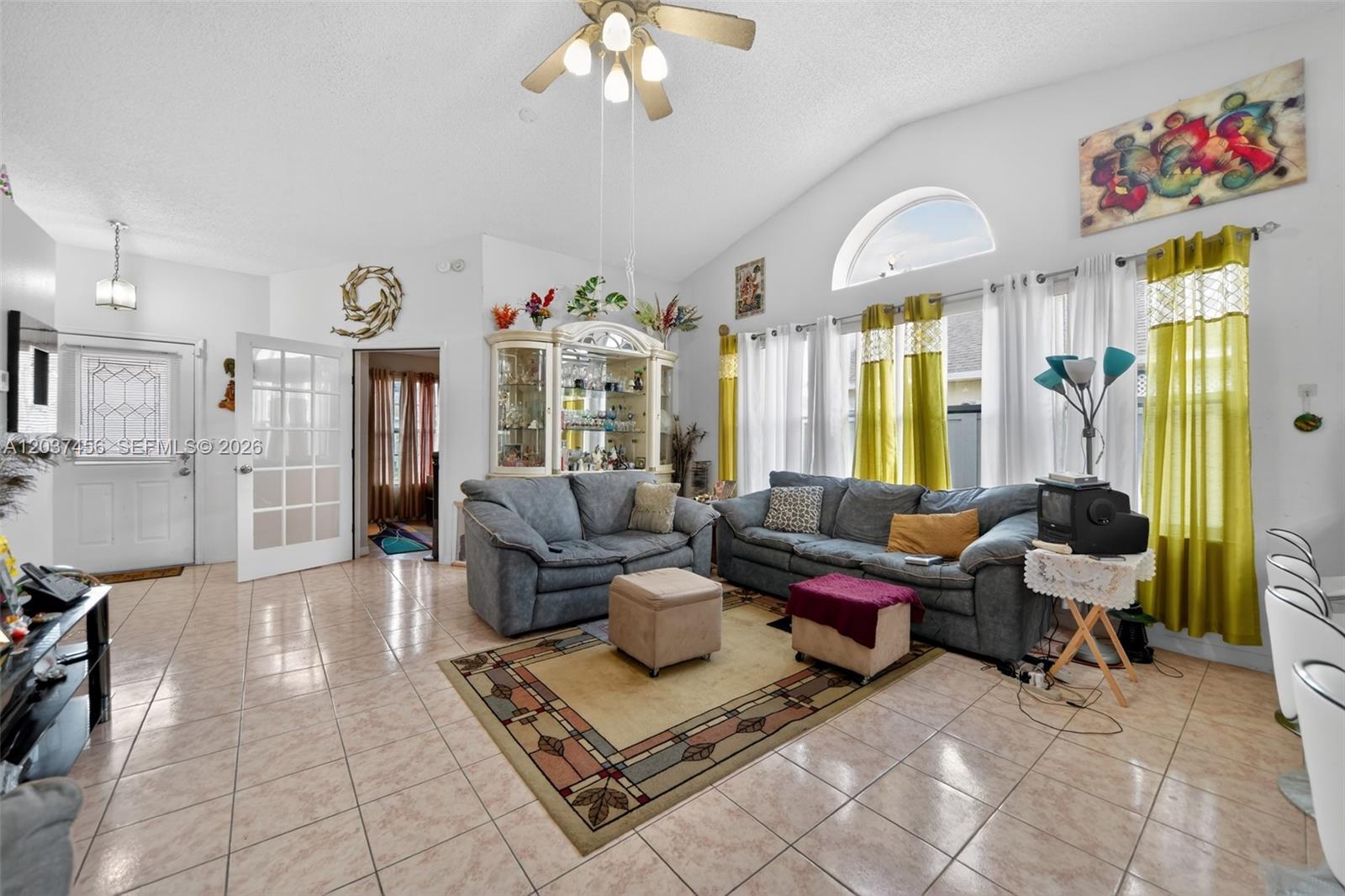 A living room features tile flooring, vaulted ceilings, two gray sofas, and yellow curtains — 362 WHITE MARSH CIRCLE, Orlando FL 32824, ORLANDO, FL