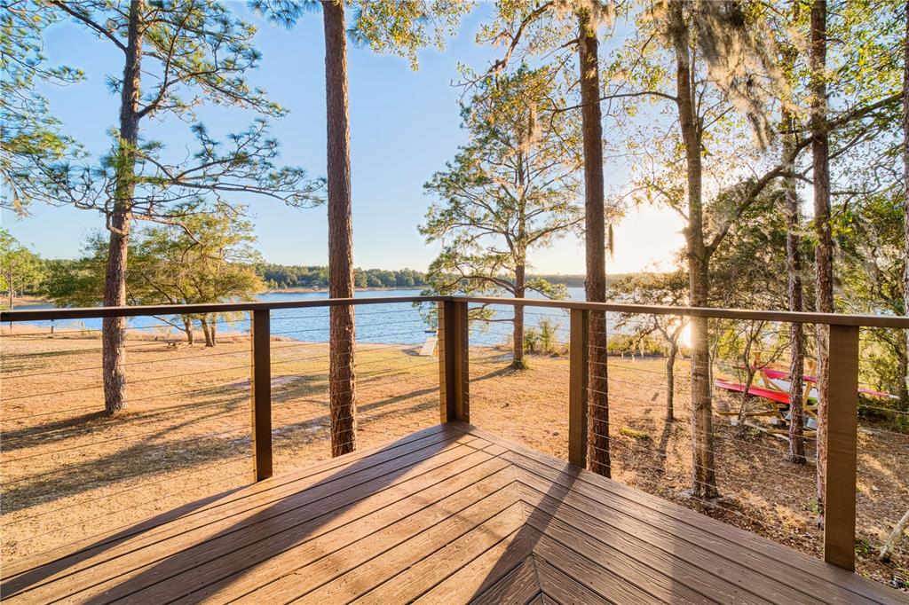 A wooden deck with a cable railing overlooks a grassy yard and a lake — 123 MASON LAKE TRAIL, HAWTHORNE, FL