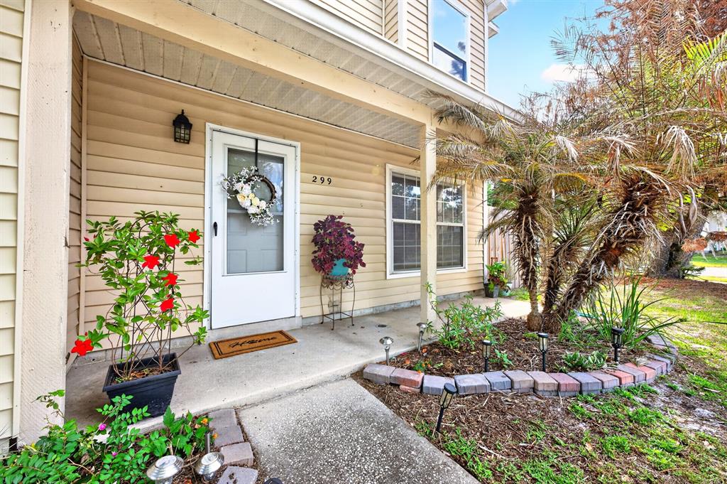 The exterior of a house features beige siding, a front door with a wreath, and landscaping — 299 WOODGREEN LANE, WINTER SPRINGS, FL