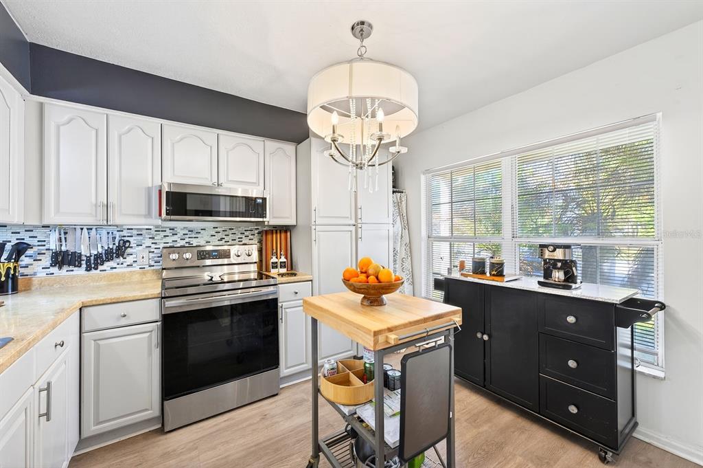 A kitchen features white cabinets, stainless steel appliances, a wooden island, and a black sideboard — 299 WOODGREEN LANE, WINTER SPRINGS, FL