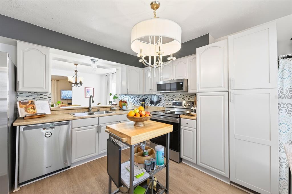 A kitchen features light gray cabinets, stainless steel appliances, a wood-topped island, and pendant lighting — 299 WOODGREEN LANE, WINTER SPRINGS, FL