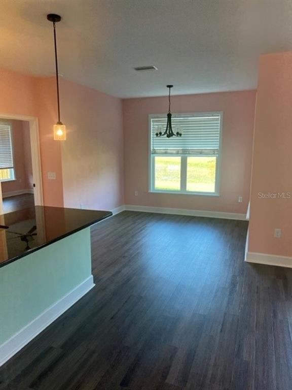 A dining area with pink walls, dark wood floors, and two hanging light fixtures — 12518 NW 159TH WAY, ALACHUA, FL