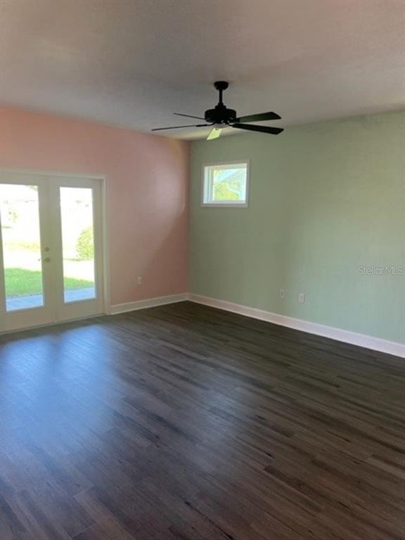 An empty room features wood-look flooring, a ceiling fan, and walls painted pink and green — 12518 NW 159TH WAY, ALACHUA, FL