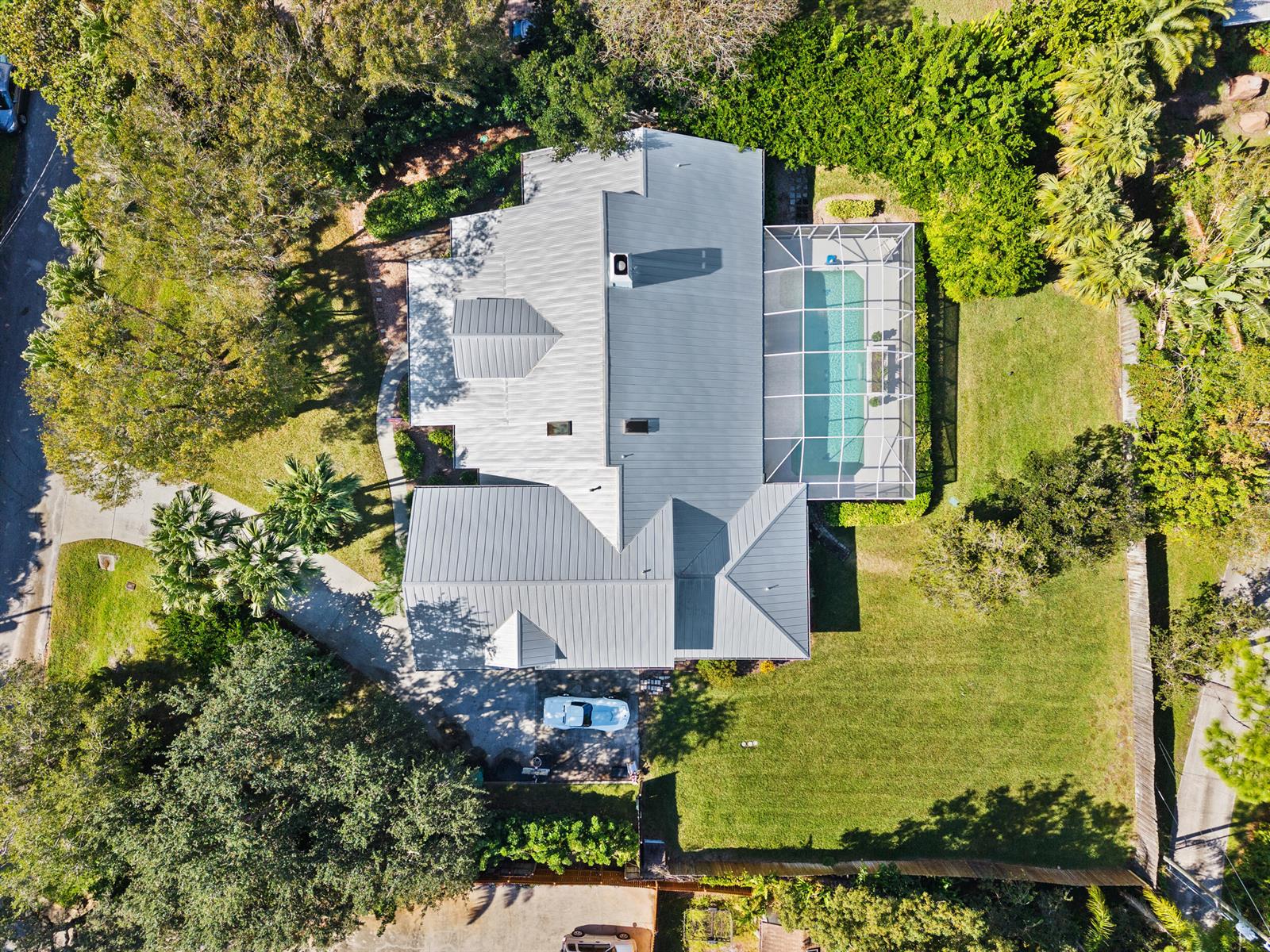 An aerial view shows a house with a metal roof, a screened-in pool, and landscaping — 619 Fischer Hammock Road, Sebastian FL 32958, SEBASTIAN, FL