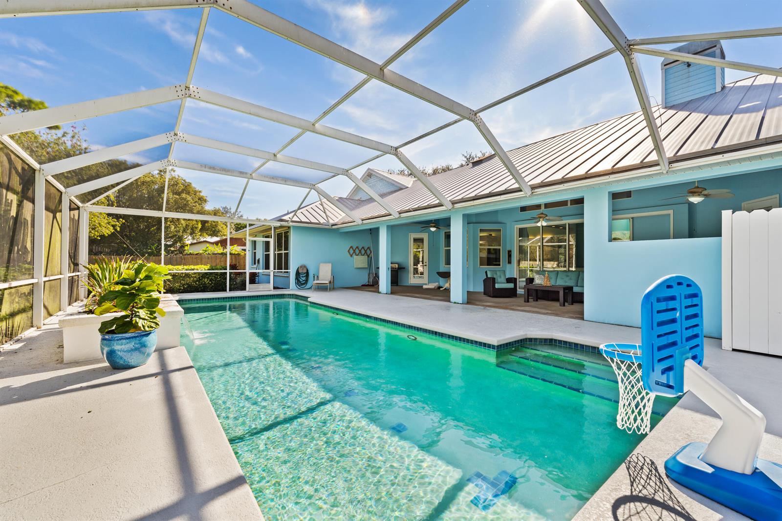 A screened-in pool patio features a rectangular swimming pool, a basketball hoop, and covered seating — 619 Fischer Hammock Road, Sebastian FL 32958, SEBASTIAN, FL