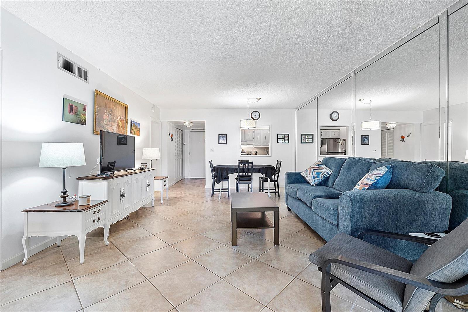 A living room features tiled floors, a blue sofa, a dining area, and mirrored walls — 5621 SW 2nd Court # 201, Margate FL 33068, MARGATE, FL