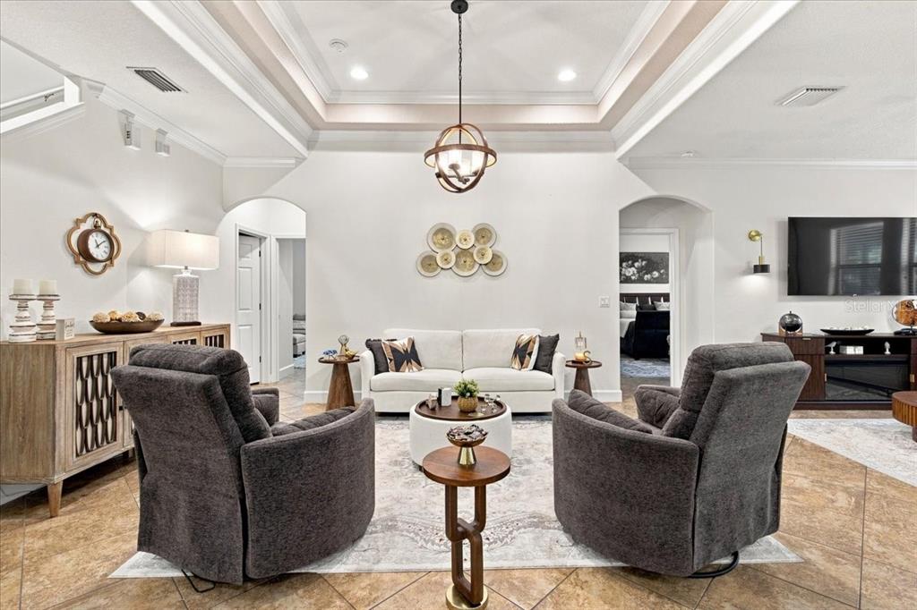 A living room features a tray ceiling, two gray armchairs, and a white sofa — 4508 GRAND LAKESIDE DRIVE E, PALM HARBOR, FL