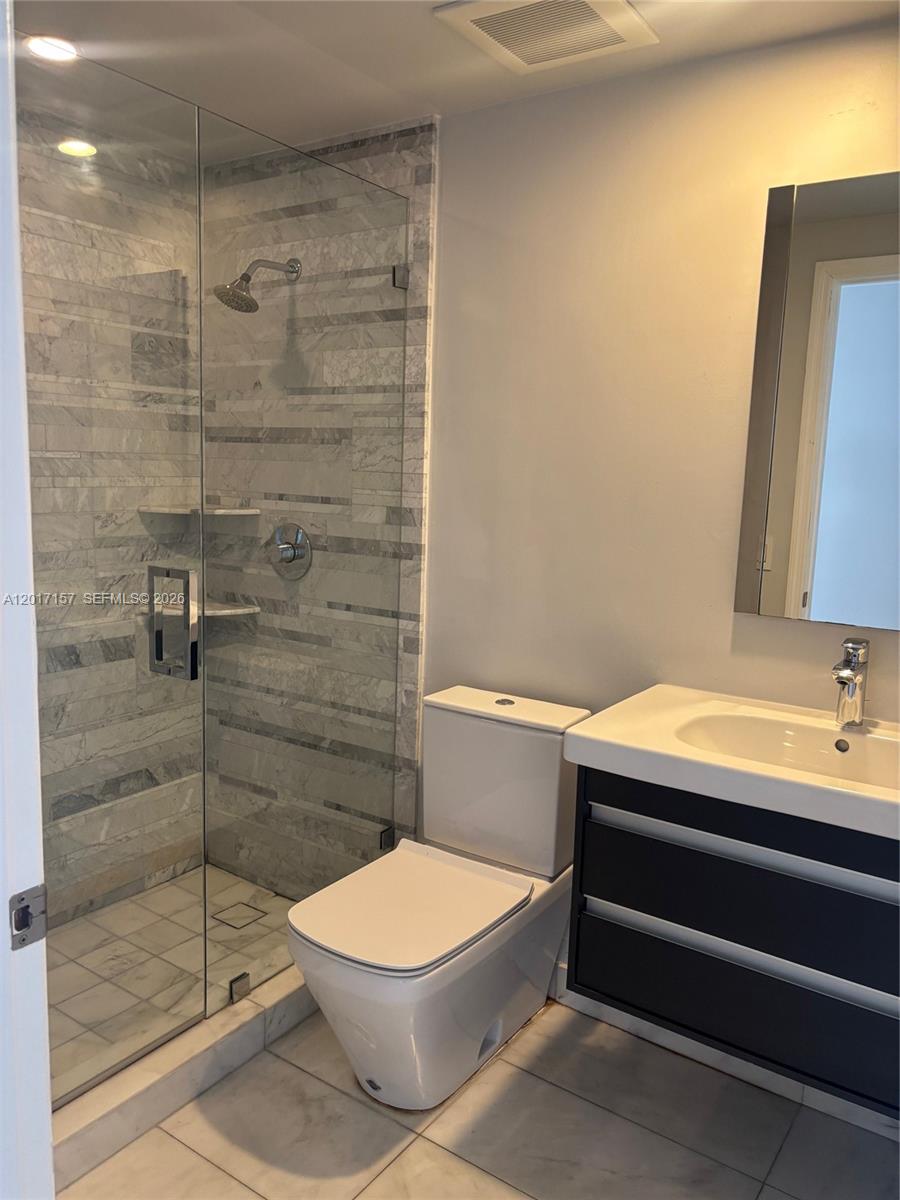 A modern bathroom features a glass-enclosed shower, a white toilet, and a dark vanity — 50 Ocean Lane Dr # 404, Key Biscayne FL 33149, KEY BISCAYNE, FL