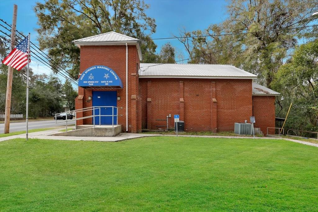 A brick Masonic Center building with a blue awning and an American flag on a pole — 18616 NW 241ST STREET, HIGH SPRINGS, FL