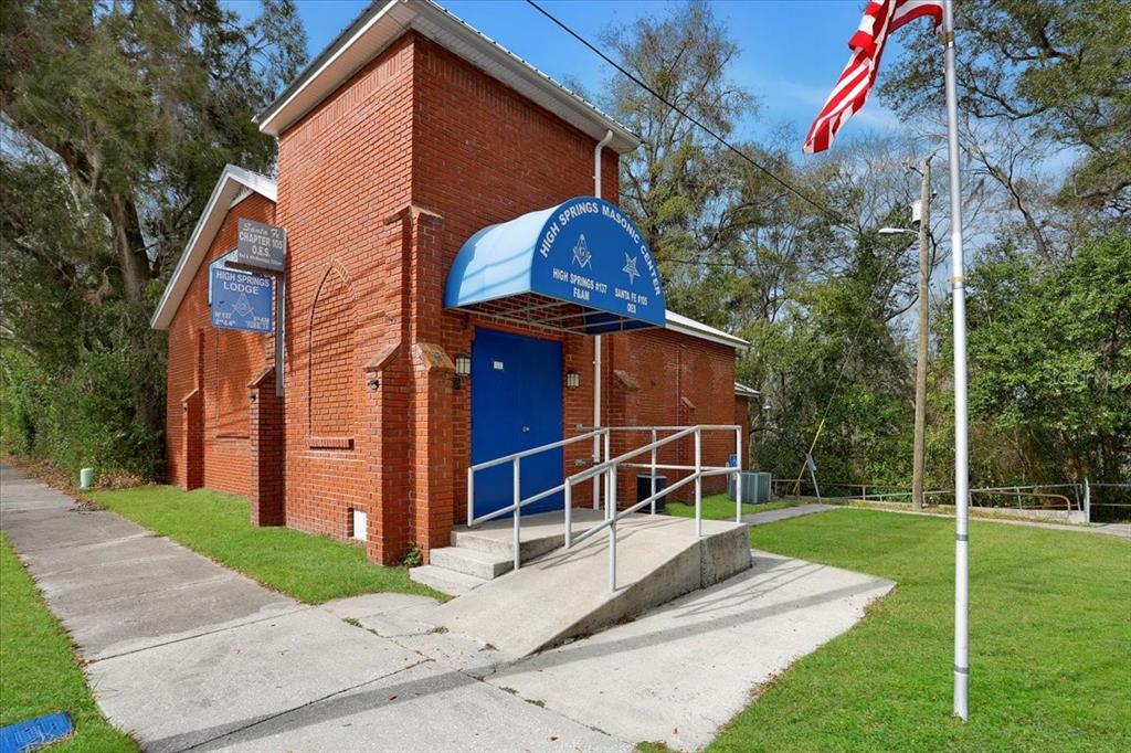 A red brick Masonic lodge building features a blue awning, a ramp, and an American flag — 18616 NW 241ST STREET, HIGH SPRINGS, FL