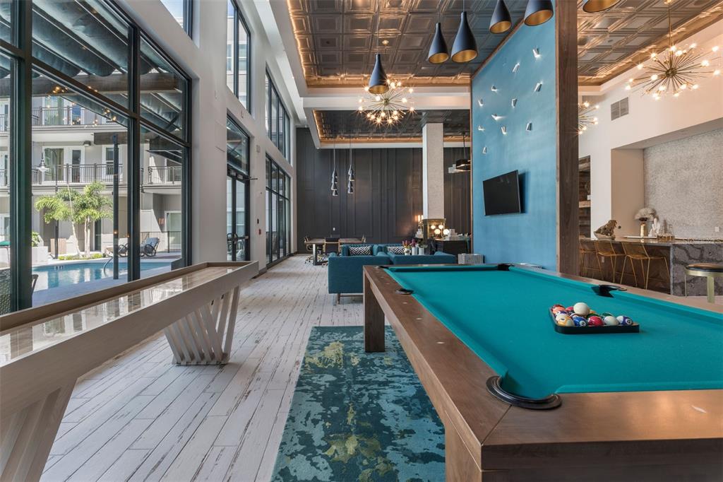 A modern apartment clubhouse featuring a pool table, shuffleboard, and views of an outdoor pool — 733 MAIN LN LANE, ORLANDO, FL